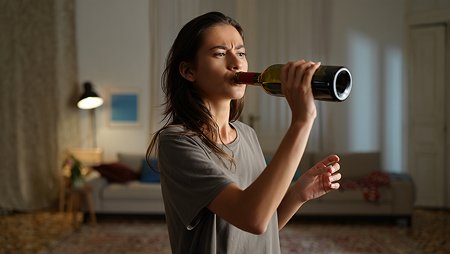 Девушка пьет вино из горла бутылки